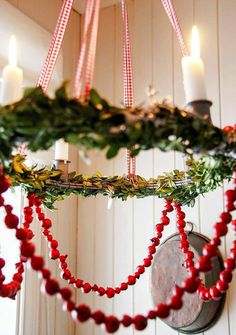 a chandelier decorated with red beads and greenery