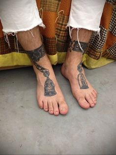 a person with tattoos on their feet standing next to a bed