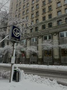 a street sign in front of a building with snow on the ground and trees around it