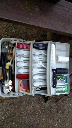 an open white case filled with utensils and other kitchen items sitting on the ground