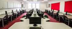 an empty room with desks and computers on it's sides in front of red partitions