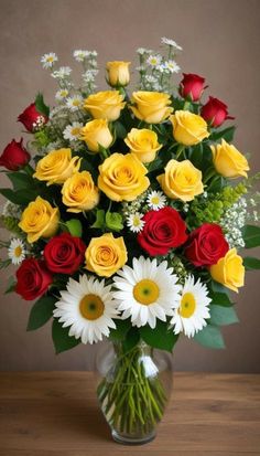 a vase filled with red, yellow and white flowers on top of a wooden table