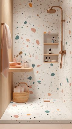 Trendy shower with terrazzo-look tiles featuring specks of pastel colors like pink, mint, and blue on a white background, natural wooden shelving, and soft warm lighting. Terrazo Tile Small Bathroom Ideas, Colorful Terrazzo Bathroom, Patterned Tile Bathroom Wall, Peach Terrazzo Bathroom, Bathroom Ideas Terrazzo, Kids Small Bathroom Ideas, Terazzo Bathroom Interior Design, Shower Tiles Design Ideas, Terrazzo Tiles Bathroom