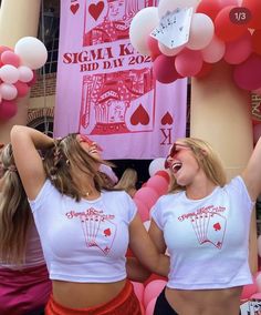 two women in white shirts and red skirts are dancing with balloons on the wall behind them