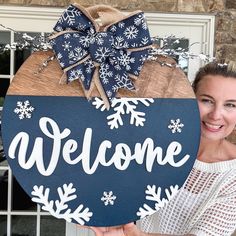 a woman holding up a welcome sign with snowflakes on it