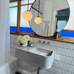 a bathroom with a sink, mirror and flower vase in the corner on the counter