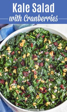 kale salad with cranberries in a white bowl on a blue and white towel