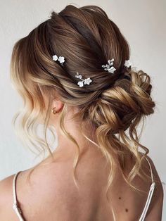 a woman with blonde hair and white flowers in her hair is shown from the back