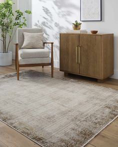 a living room area with a chair, rug and potted plant on the floor