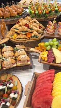 a table filled with lots of different types of food on wooden trays next to each other