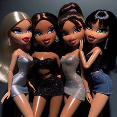 four dolls are posed together in front of a gray background