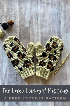 two knitted mittens sitting on top of a wooden floor next to knitting needles