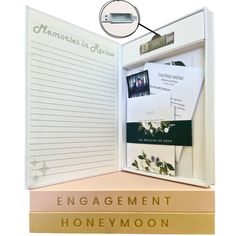 an open book with writing on it and some papers attached to the front cover that reads engagement honeymoon