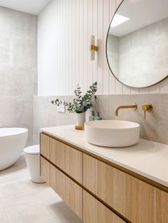 a bathroom with a sink, mirror and bathtub next to a plant on the counter