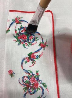 a painting brush is being used to paint a floral design on a white table cloth