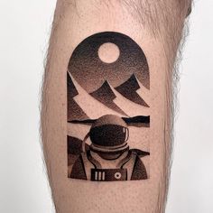 a man's leg with a black and white tattoo on it that has an astronaut looking at the moon