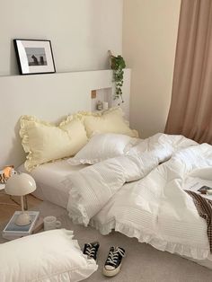 an unmade bed in a bedroom with white sheets and pillows on top of it