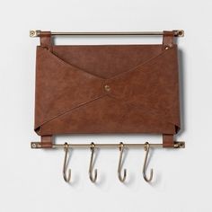 a brown leather purse hanging on a wall with two hooks attached to it and an umbrella hook