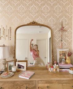 a woman taking a selfie in front of a mirror on top of a dresser