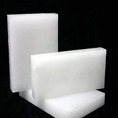 three pieces of white soap sitting on top of each other in front of a black background