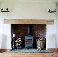 a wood burning stove sitting inside of a living room next to a pile of logs