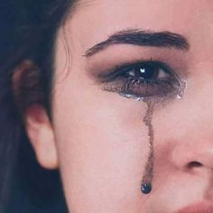 a woman with tears on her face and eyeliners, looking at the camera