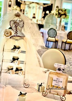 a table topped with a bottle of perfume next to a dress on top of a mannequin