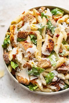 a pasta salad with chicken, lettuce and parmesan cheese in a bowl