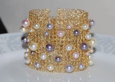 a close up of a bracelet on a plate with pearls and chains around it's edges