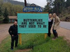 three people standing next to a sign that says butterflies are not what they used to be