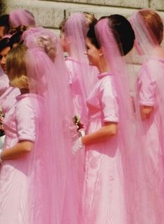 a group of women in pink dresses standing next to each other with veils over their heads