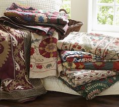 a pile of blankets sitting on top of a wooden floor next to a basket and window