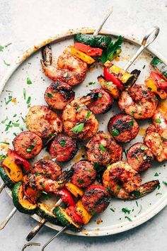 grilled shrimp and vegetable kabobs on a plate with tongs, garnished with parsley