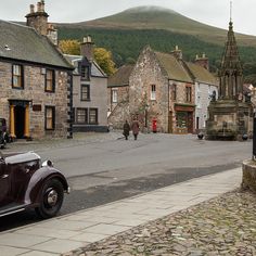 an old car is parked on the side of the road in front of some buildings