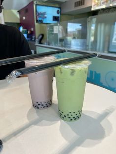 two drinks sitting on top of a white table in front of a man with glasses