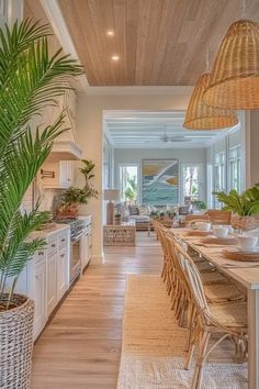 a dining room and kitchen area in a house with wood ceilinging, wicker furniture and large palm trees