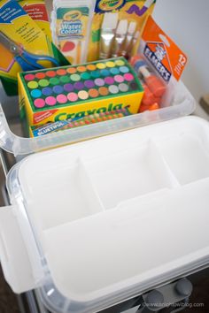 a plastic container filled with lots of different types of markers and pencils on top of a table