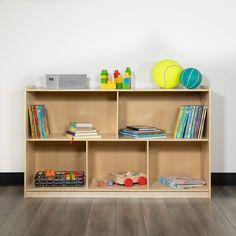 a wooden shelf with books and toys on it in a white walled room next to a wall