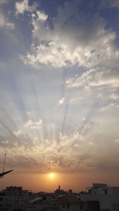 the sun is shining through the clouds in the sky over some buildings and rooftops