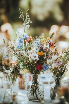 three vases filled with flowers sitting on top of a table