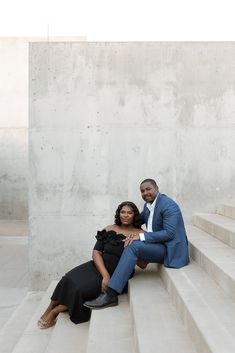 a man and woman are sitting on some steps posing for the camera with their arms around each other