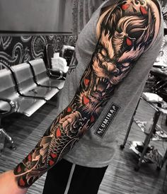 a man's arm with a dragon tattoo on it and red hearts in the middle