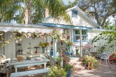 a white house with blue trim and flowers on the porch