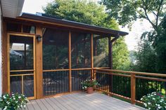 a screened porch with potted plants on the deck