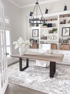 a dining room table with white flowers in vases on the top and shelves behind it