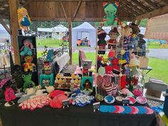 there are many stuffed animals on display under the tent at this outdoor market stall where people can buy and sell them