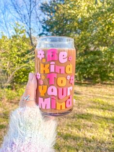 a person holding up a cup with the words be kind to you mom on it