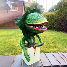 a statue of a frog with its mouth open and tongue out, sitting on top of a box