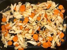 chopped carrots and onions cooking in a black skillet on the stove top,