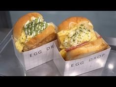 two sandwiches with eggs and cheese in paper containers